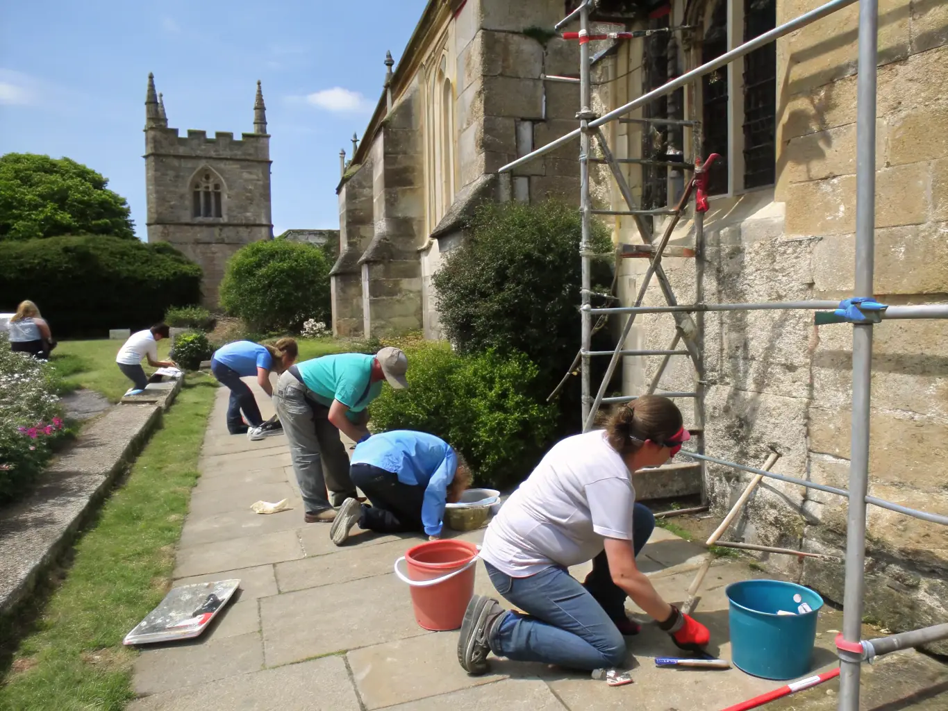 A group of volunteers working together to restore a section of the Moulin de la Croix, focusing on the wooden structure and traditional building techniques.